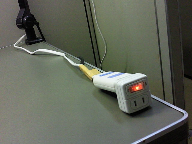 改造された節電タップがテーブル上に置かれ、電源が入っている状態の画像